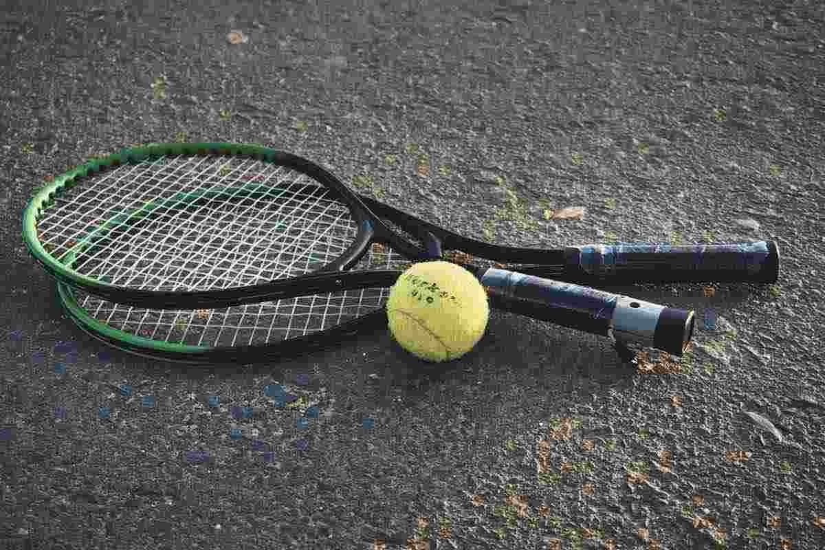 Racchette e pallina da tennis per terra